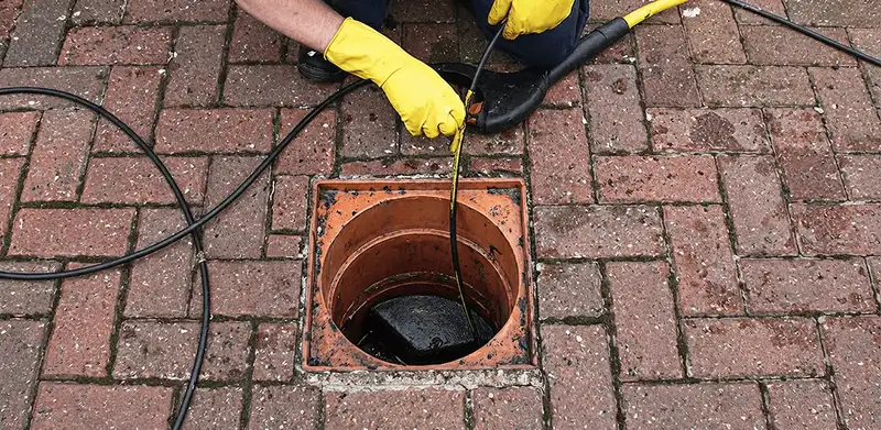 Drain cleaning technician using a drain snake to clear a clogged drain in Columbus, OH