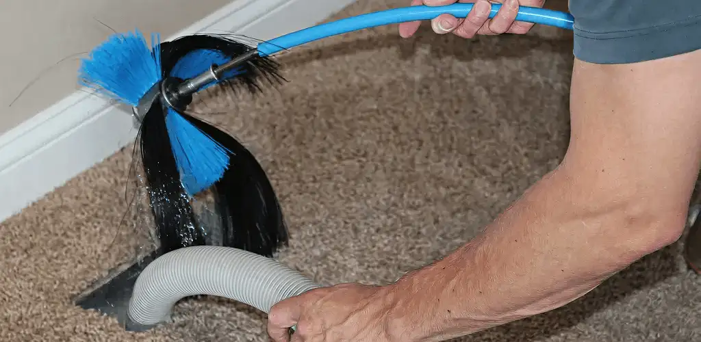 Dryer vent cleaning technician brushing lint from a vent line in Columbus, OH