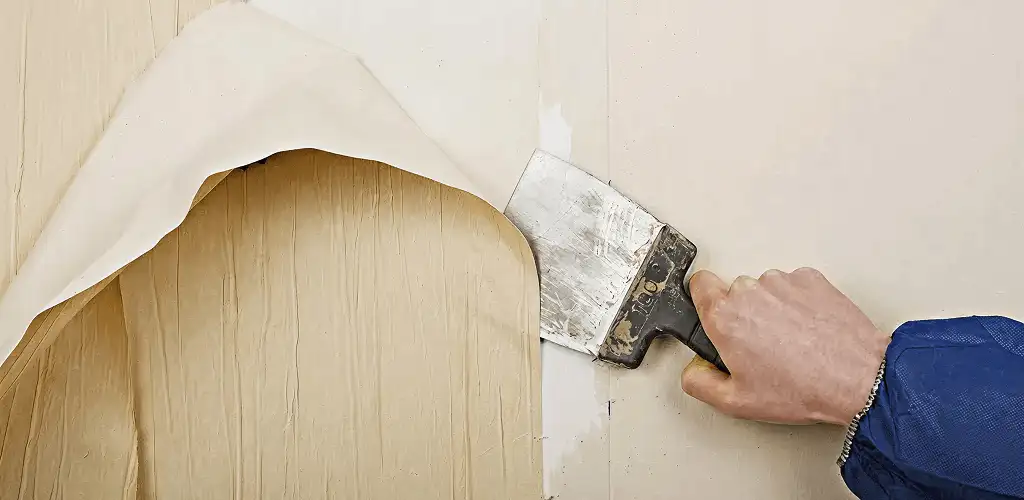 Handyman removing wallpaper with a scraper for wall preparation in Columbus, OH