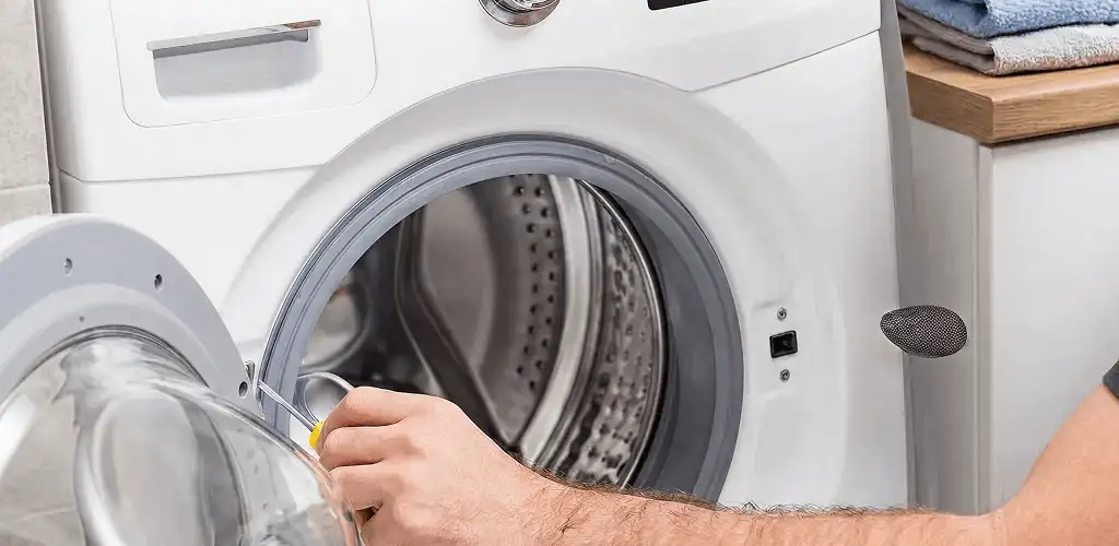 Handyman repairing a front-load washing machine and inspecting the drum in Columbus, OH