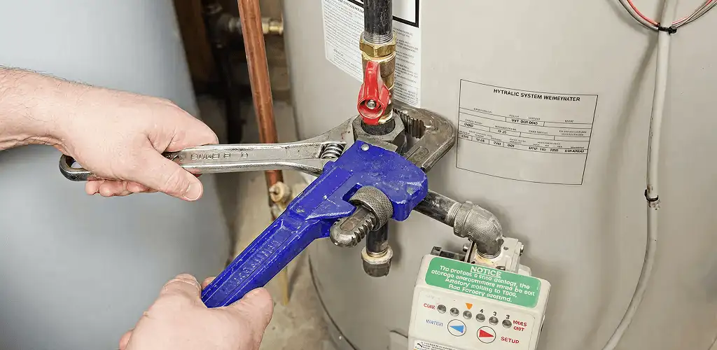 Water heater repair technician tightening the shutoff valve and supply line in Columbus, OH